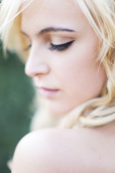 a woman with blonde hair and blue eyeshadow is looking down at her cell phone