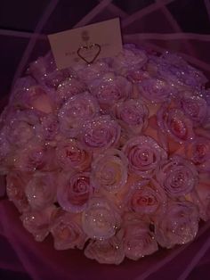 a bouquet of pink roses with water droplets on it and a card in the middle