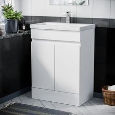 a white bathroom sink sitting next to a black and white tiled wall in front of a window