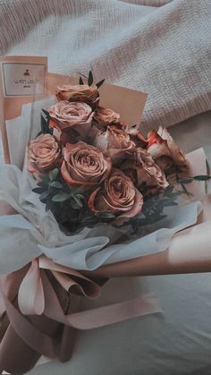 a bouquet of roses sitting on top of a bed next to a card and envelope