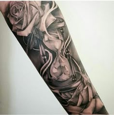 a black and white tattoo with an hourglass and roses