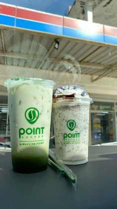 two drinks sitting on top of a table next to each other in front of a store