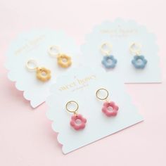 three pairs of earrings with doughnuts on them sitting next to each other in front of a pink background