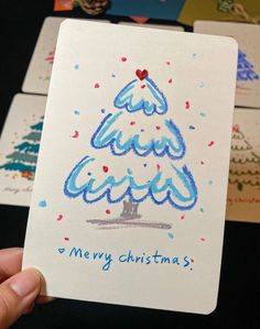 a hand holding up a christmas card with the words merry christmas written in blue on it