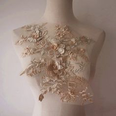 a white mannequin with gold flowers and leaves on it's back side