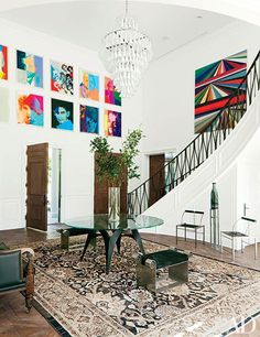 a living room filled with furniture and paintings on the wall above it's stairs