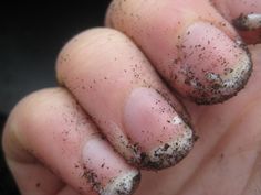 a person with brown and black nail polish holding up their thumb to the camera while it is covered in dirt