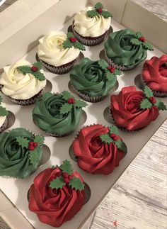 twelve cupcakes with green and red frosting in a box on a table