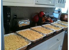 several trays of macaroni and cheese on a kitchen counter