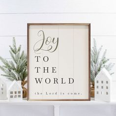 a wooden sign that says joy to the world on top of a mantle with small white houses