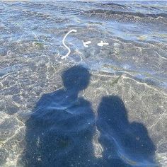 two people are standing in the water with their shadows