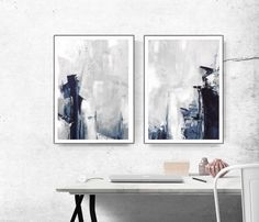 two paintings are hanging on the wall above a white desk and chair in an office