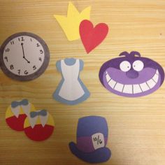 some cut outs are on a table with a clock and other things around them that look like cartoon characters