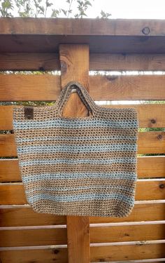 a crocheted bag hanging from a wooden bench with wood slats in the background