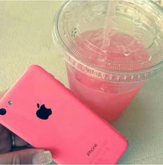 a person holding an iphone in front of a drink