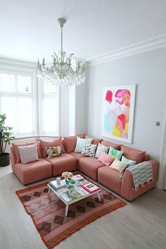 a living room filled with furniture and a chandelier hanging from the ceiling over a rug