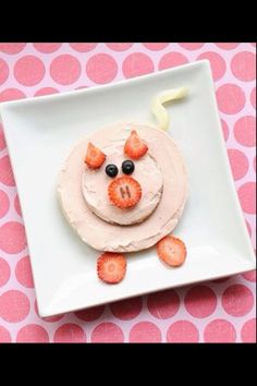 a white plate topped with a cake covered in frosting and strawberries on top of it