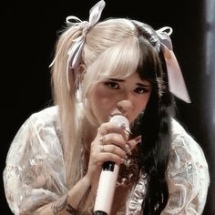 a woman with long hair holding a microphone in her hand and wearing a bow around her head