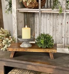 a wooden table topped with plants and a lit candle