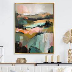 an abstract painting hangs on the wall above a white couch and coffee table in a living room