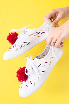 someone is holding their white shoes with colorful sprinkles and pom - poms