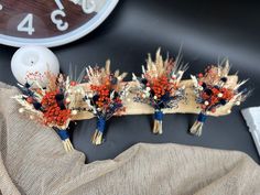 three boutonnieres with red berries and blue stems are sitting on a table next to a clock