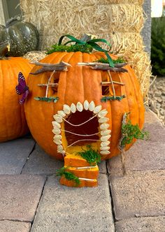 two pumpkins sitting on top of a brick walkway next to hay bales and grass