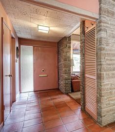 an empty hallway with red tile floors and brick walls on either side of the door