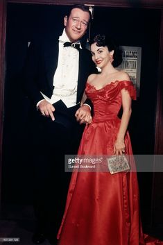 a man in a tuxedo standing next to a woman in a red dress