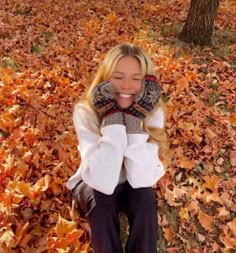 a woman sitting on the ground covered in leaves