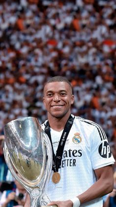 a man holding a silver trophy in front of a large crowd at a soccer game