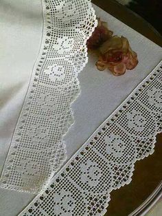 a white lace table runner with flowers on it and a piece of cloth next to it