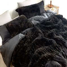 a bed covered in black and grey blankets