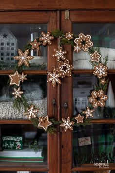 a close up of a christmas wreath on a wooden door with snowflakes hanging from it