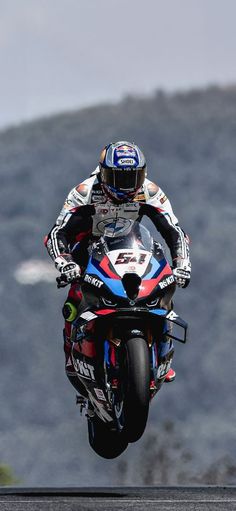 a person on a motorcycle doing a wheelie in the air with mountains in the background