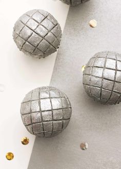 three silver balls are sitting on a table with confetti scattered around them,