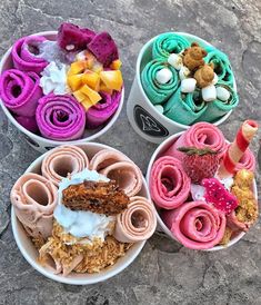 four bowls filled with different types of desserts on top of a stone slabd ground