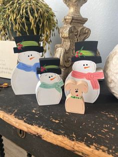 three snowmen with hats and scarfs on top of a table