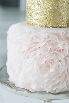 a close up of a cake with pink and gold frosting on it's top