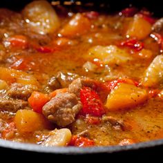 a stew with meat, potatoes and tomatoes in a pot