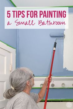 a woman is painting the walls in her bathroom