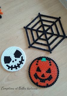 three beaded halloween coasters sitting on top of a wooden table next to a spider web