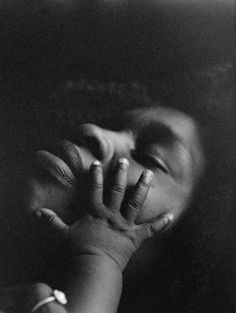 a black and white photo of a person covering their face with his hands while holding the other hand