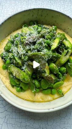 a white bowl filled with green vegetables on top of a table