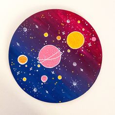 a colorful painted plate with planets and stars on it's surface, in front of a white wall