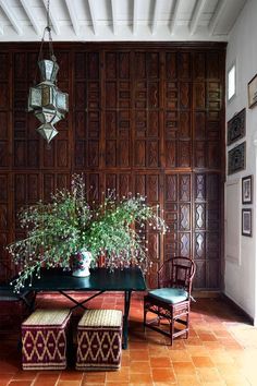 a dining room table with two chairs and a bench in front of a wooden paneled wall