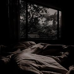 an unmade bed in front of a window