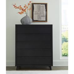 a black chest of drawers with a vase on top