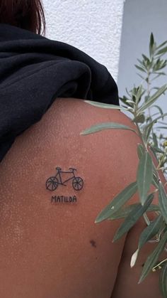 the back of a woman's shoulder with a bicycle tattoo on it