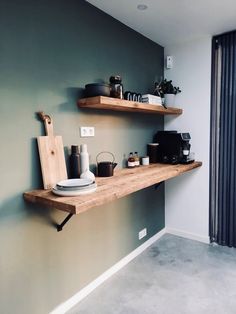 two wooden shelves on the wall with coffee cups and other items sitting on top of them